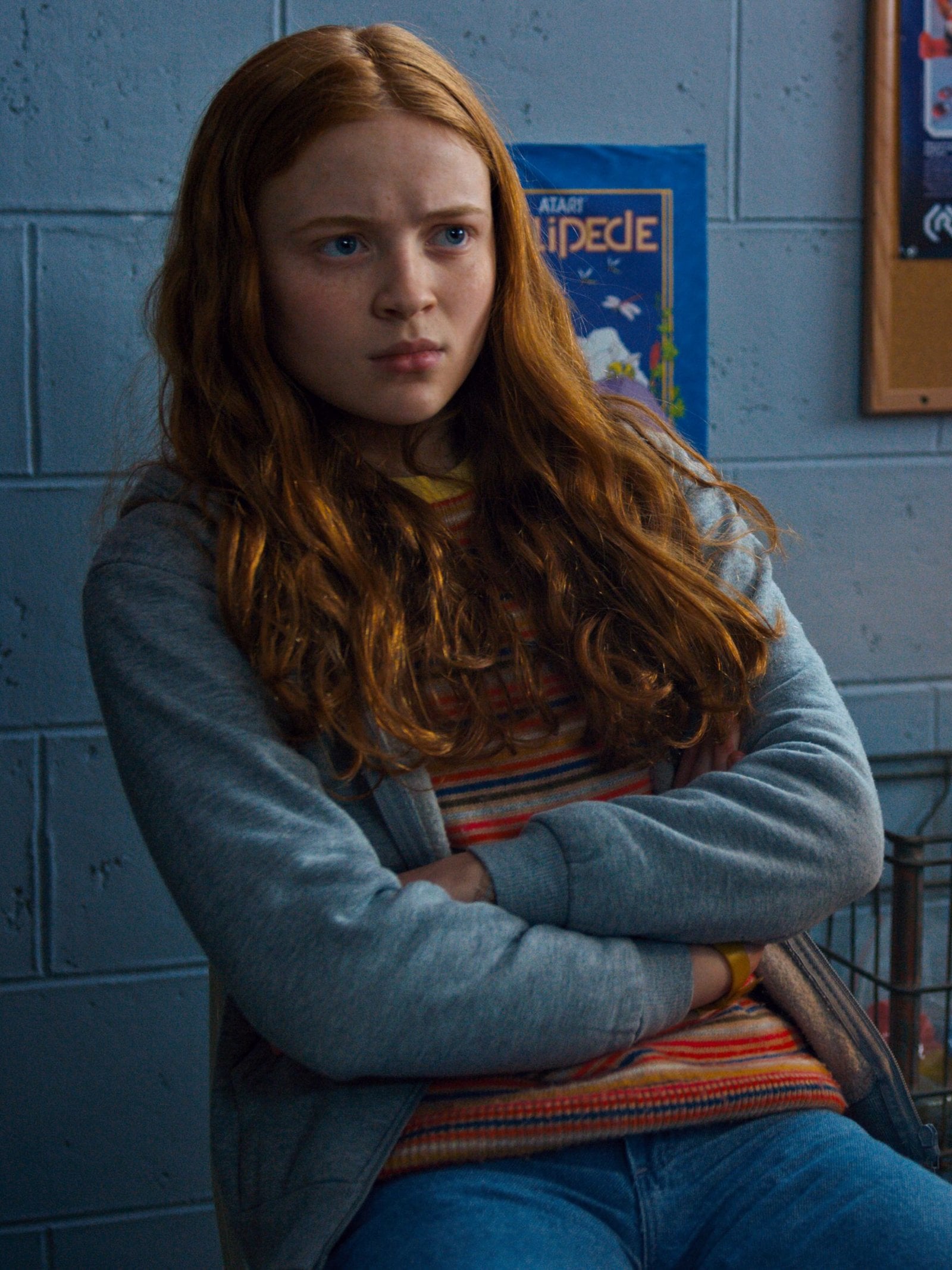 Actress Sadie Sink sits in a chair with her arms crosed in a chair in an episode of Stranger Things.